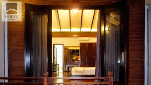 A hotel room with a wooden floor, a bed, a desk, and a view of the outside.