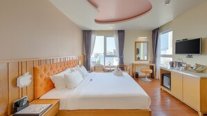 A hotel room with a large bed, a desk, a television, and a city view. - Sea Queen Hotel (Da Nang)