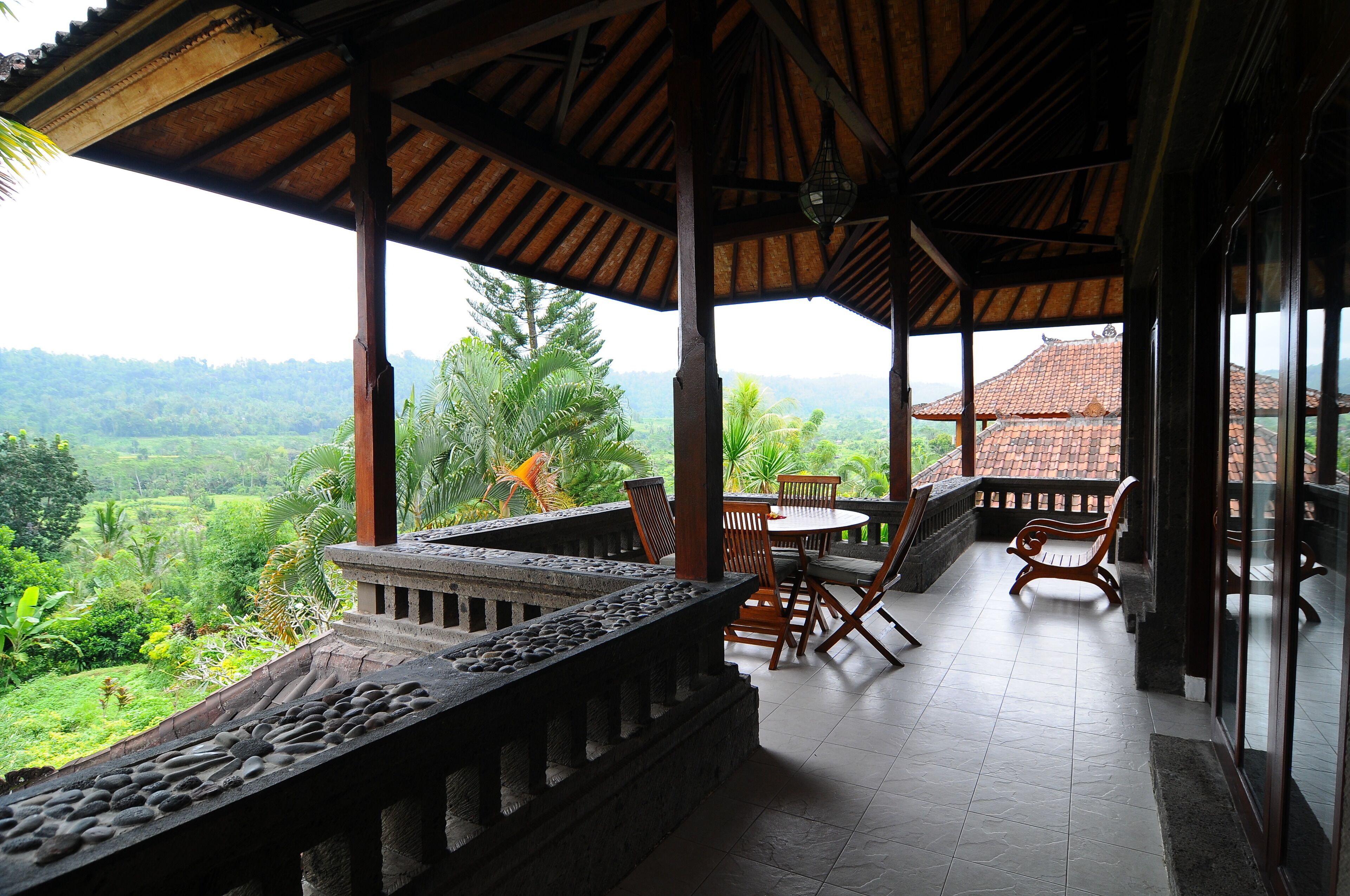 A covered outdoor seating area with a view of lush greenery and distant hills.