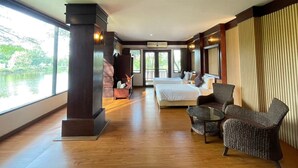Una habitación de hotel con un ventanal grande, una cama, dos sillas y una mesita.