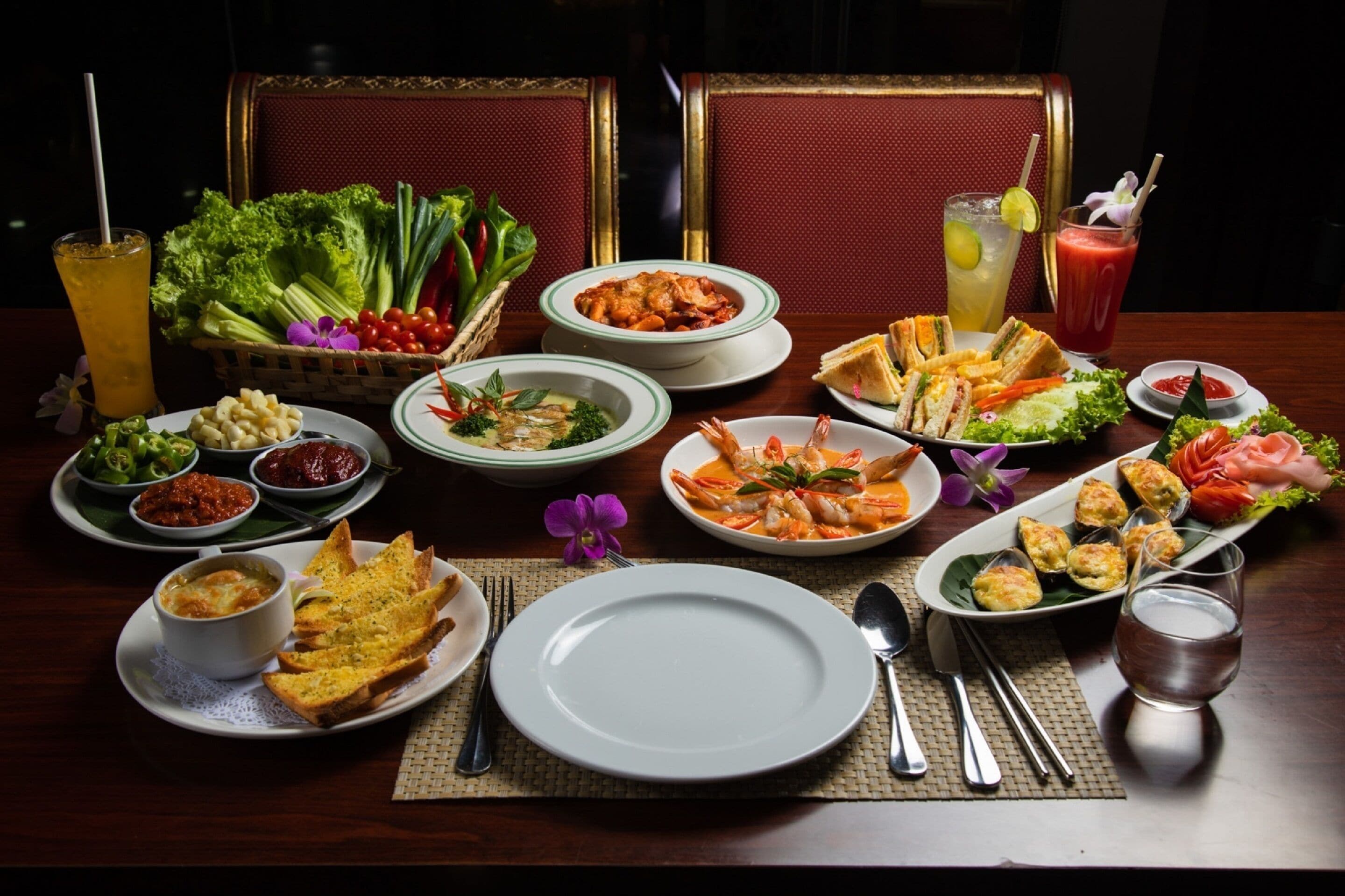 A dining table set with various dishes, including seafood, salads, and bread, along with drinks and utensils.