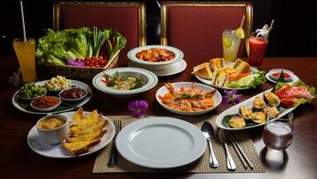 A dining table set with various dishes, including seafood, salads, and bread, along with drinks and utensils.