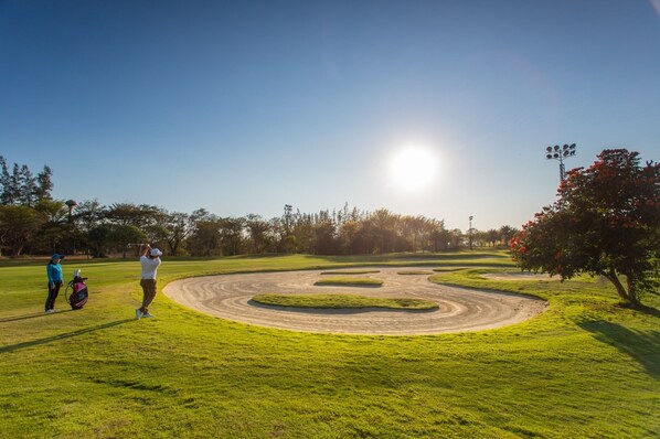 Un campo de golf bajo un cielo despejado y sol.