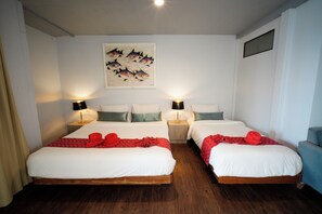 Two single beds with wooden frames and white bedding, flanked by nightstands and a large painting of fish.