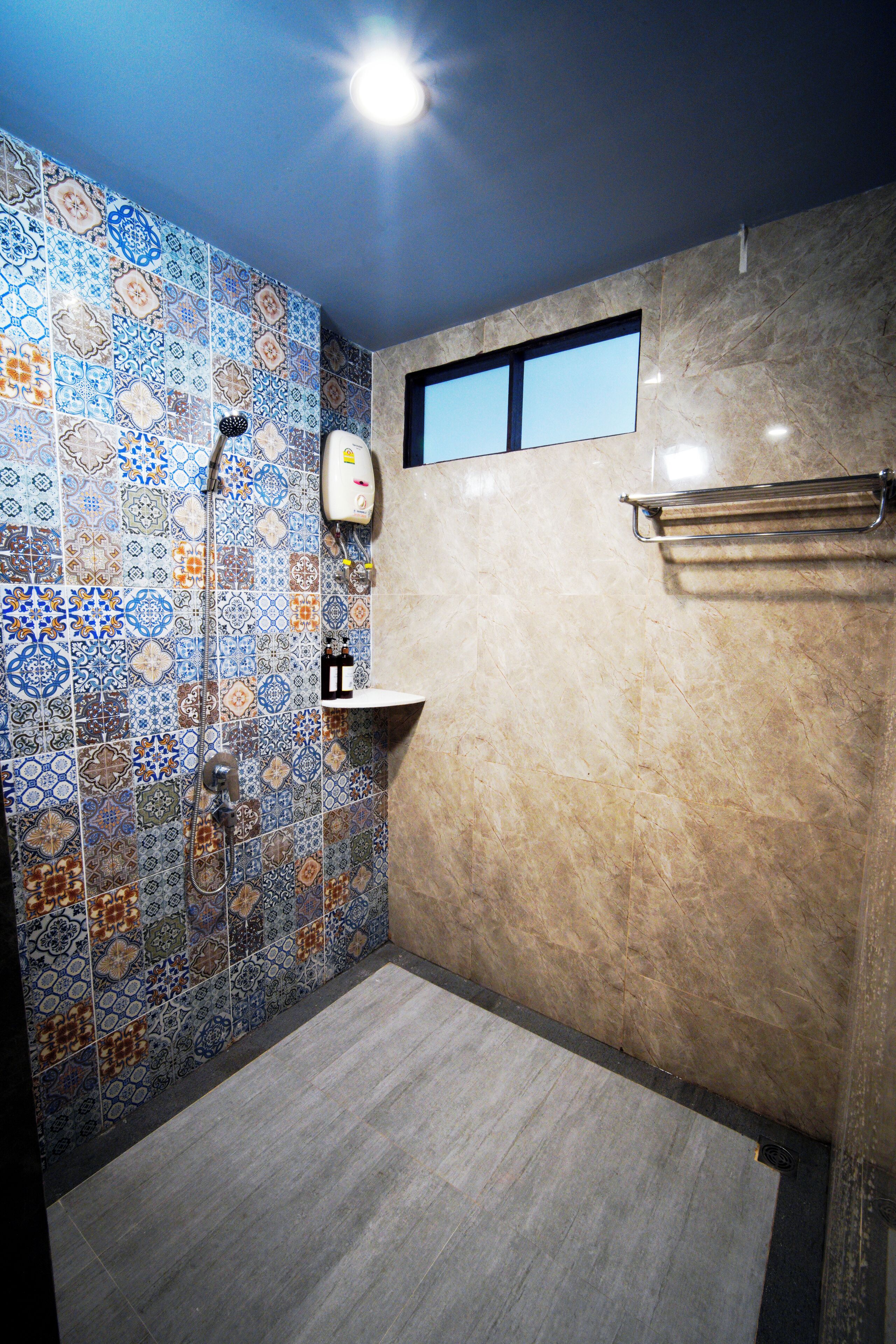 A bathroom with patterned tiles, a shower, a sink, and a towel rack.