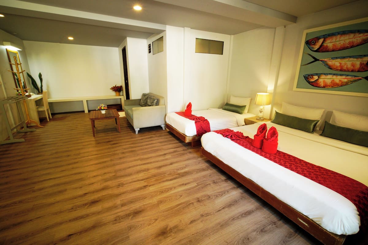 Une chambre d’hôtel avec deux lits, un bureau, une chaise et une télévision.
