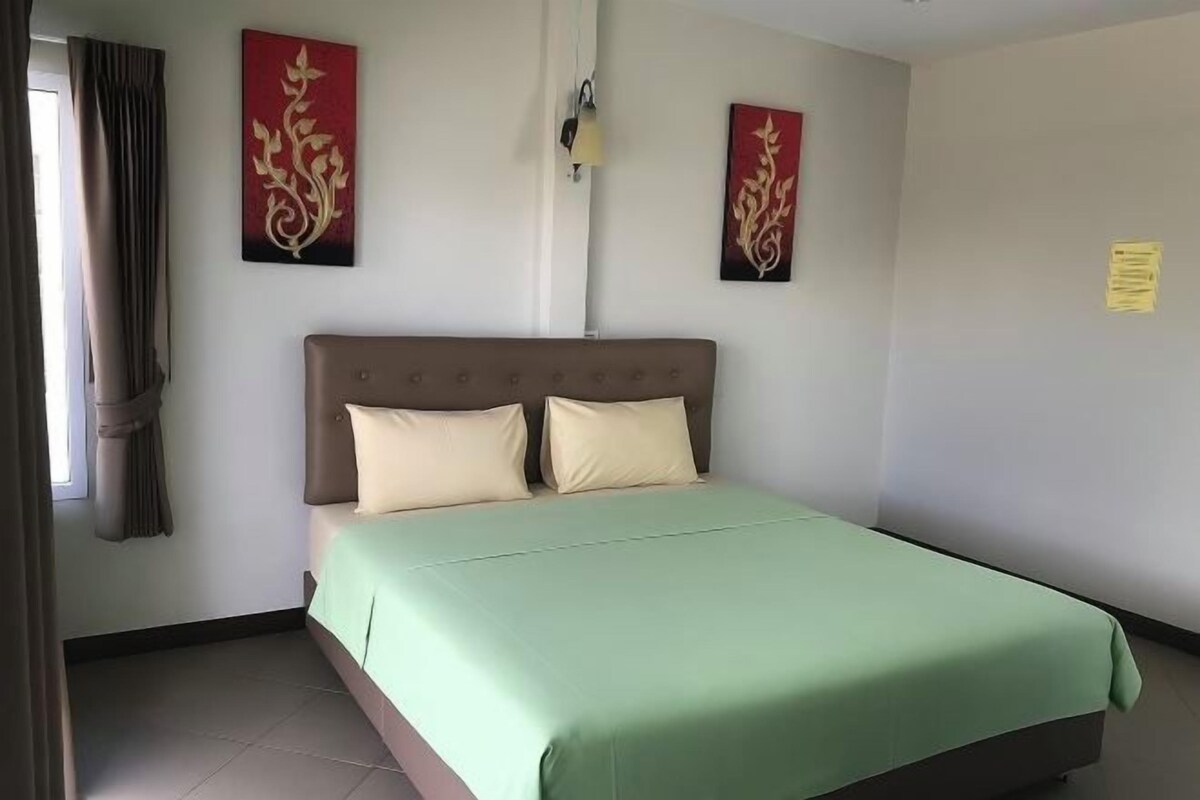 Une chambre à coucher avec un lit, des rideaux et deux œuvres d’art accrochées au mur.