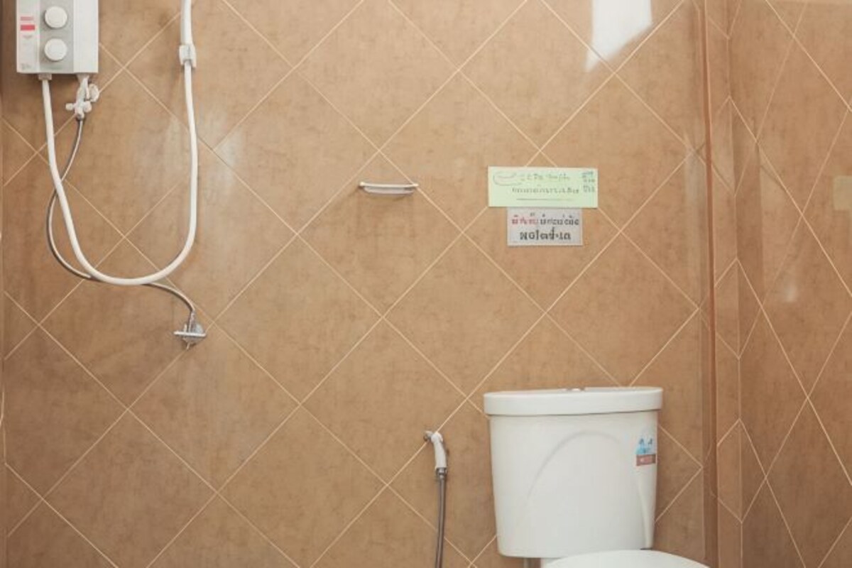 Une salle de bain équipée d’une douche, de toilettes et d’un panneau indiquant les mesures à prendre pour économiser l’eau.