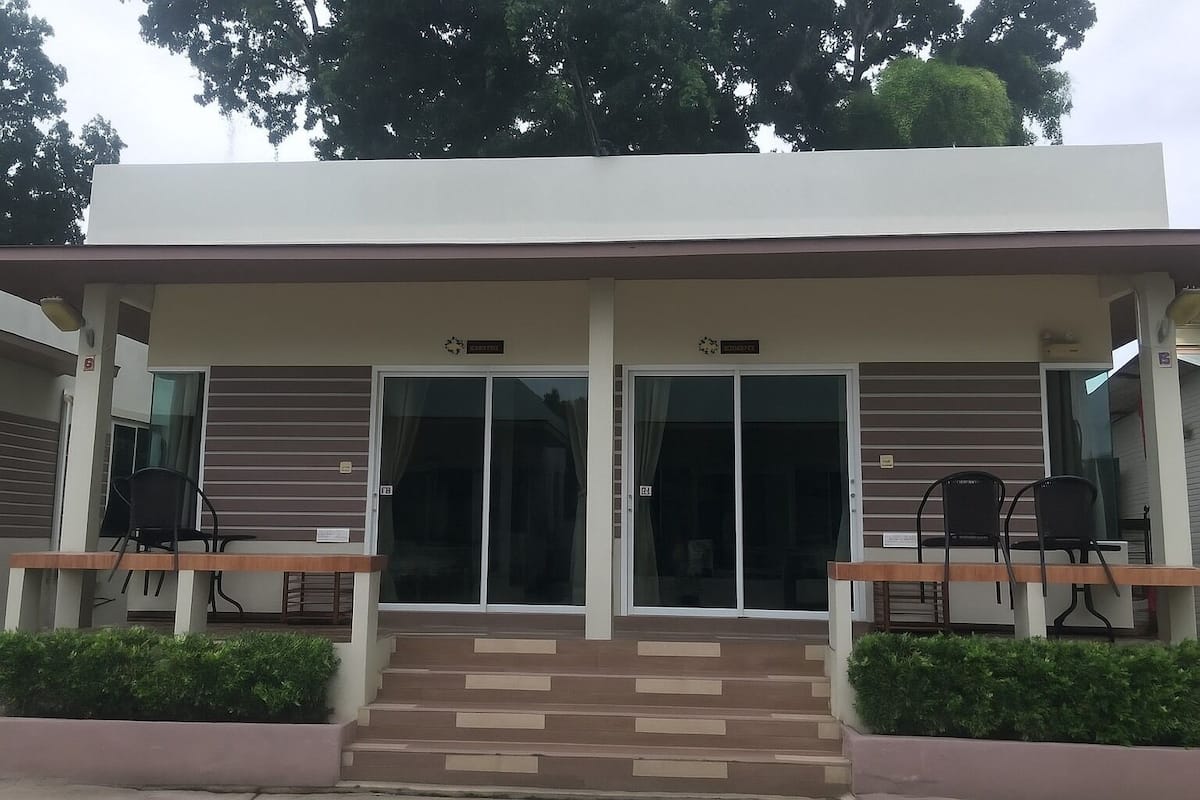 Un edificio moderno con un vestíbulo cubierto, dos sillas afuera y una escalera que lleva a la puerta.