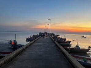 Ein Steg, der sich in ruhiges Wasser bei Sonnenuntergang erstreckt, mit Booten an beiden Seiten vertäut.