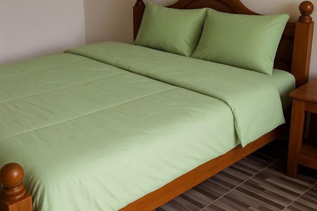 Una cama con estructura de madera y ropa de cama verde.