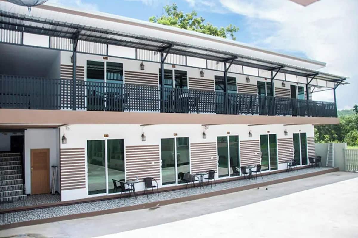 Un edificio moderno de dos pisos con una zona de estar al aire libre cubierta y una escalera que conduce a la entrada.