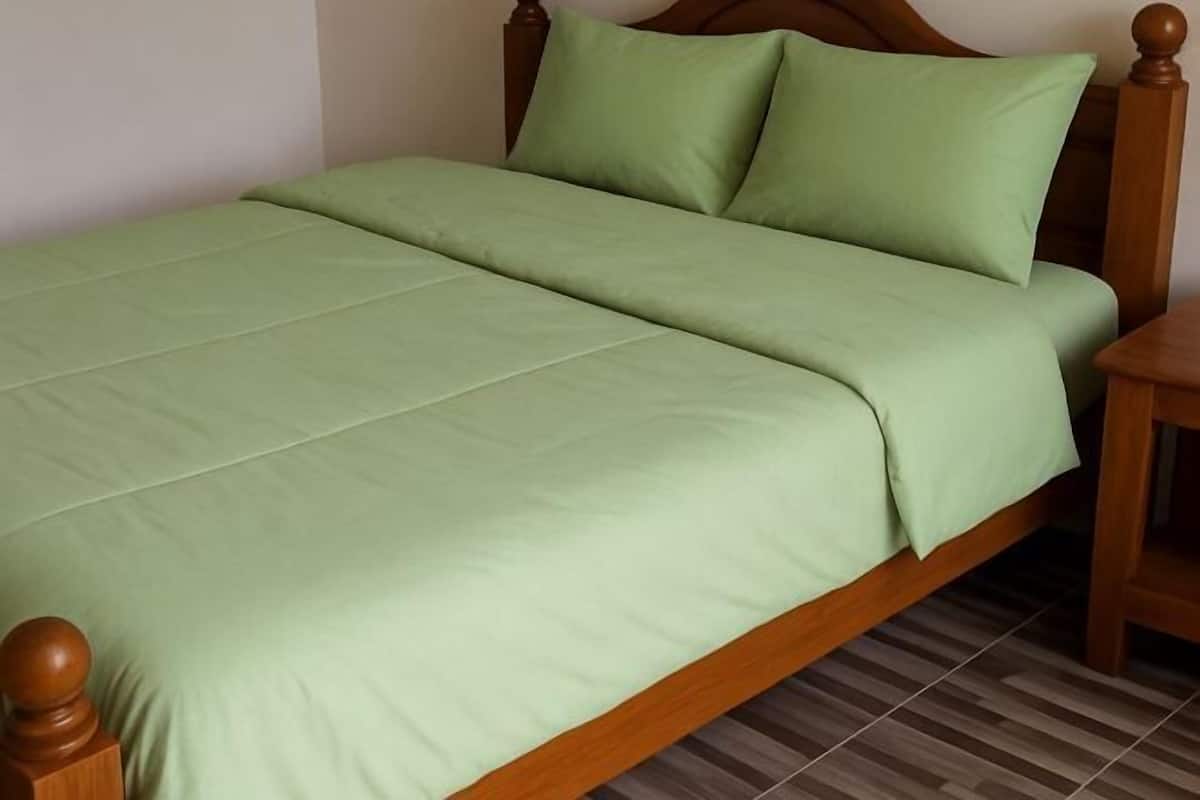 Una cama con estructura de madera y ropa de cama verde.