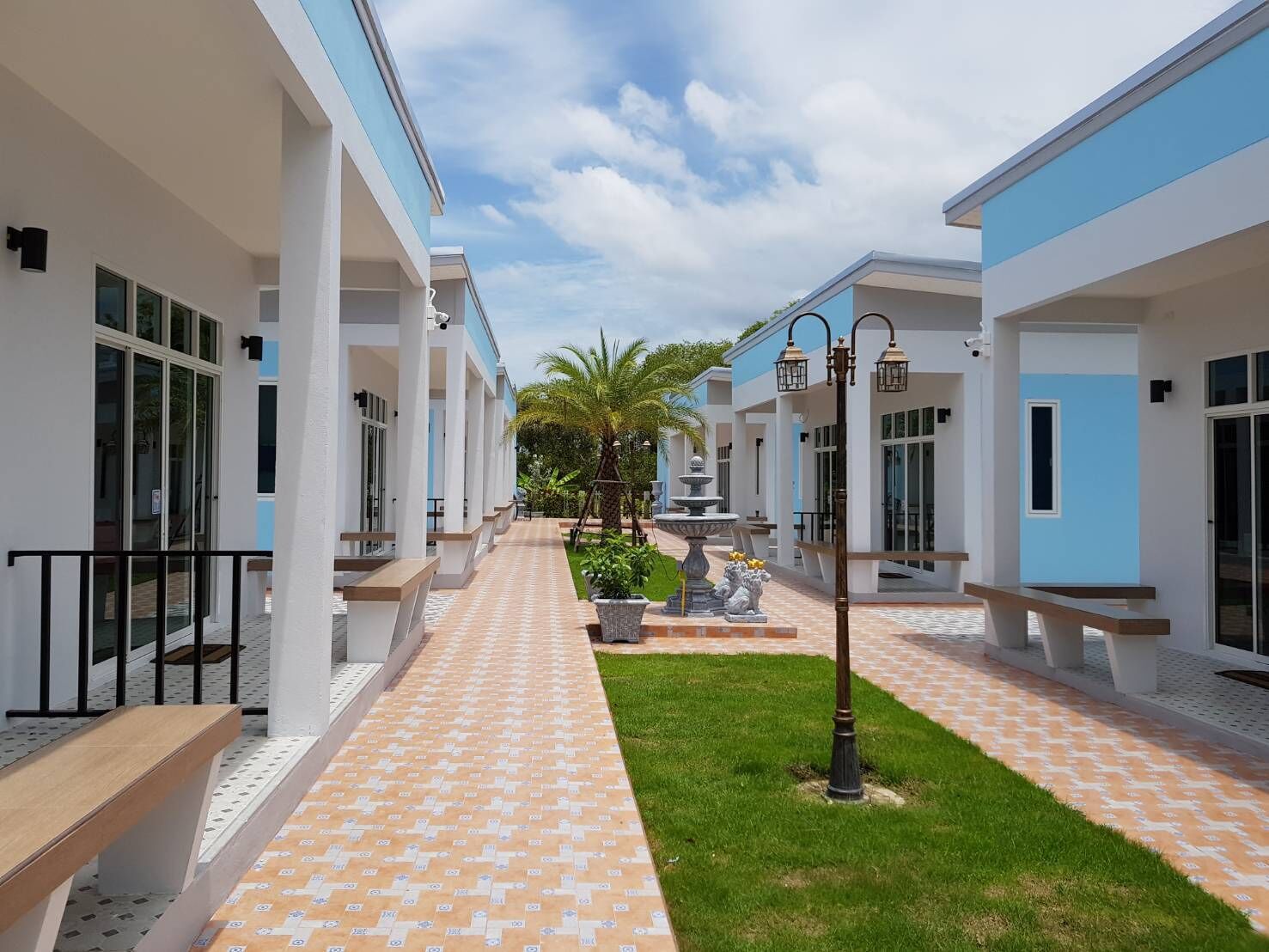 A corridor with a tiled walkway, benches, and a fountain.