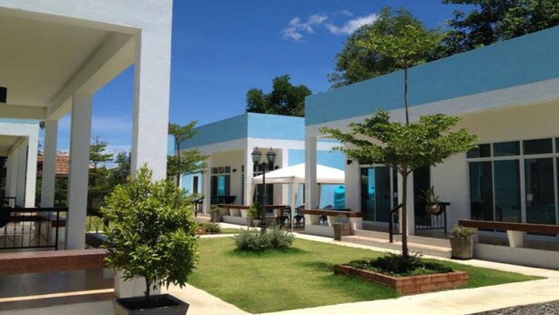 A modern building with a covered outdoor area, including seating and a small garden. - The Cube Resort (Chanthaburi)