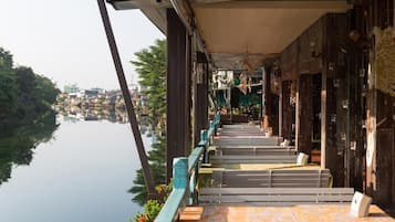 A riverside walkway with steps leading down to a river, surrounded by buildings and greenery.