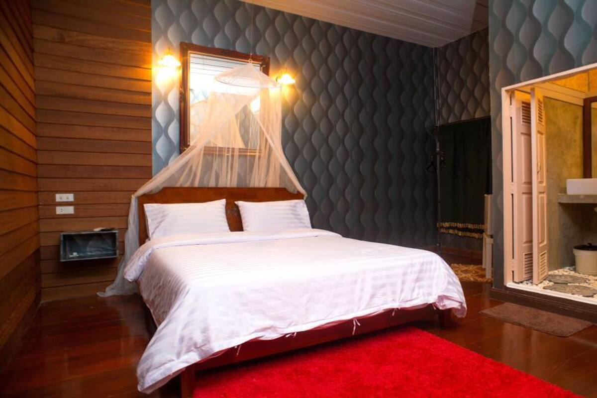 A bedroom with a four-poster bed, a red carpet, and a textured wall.
