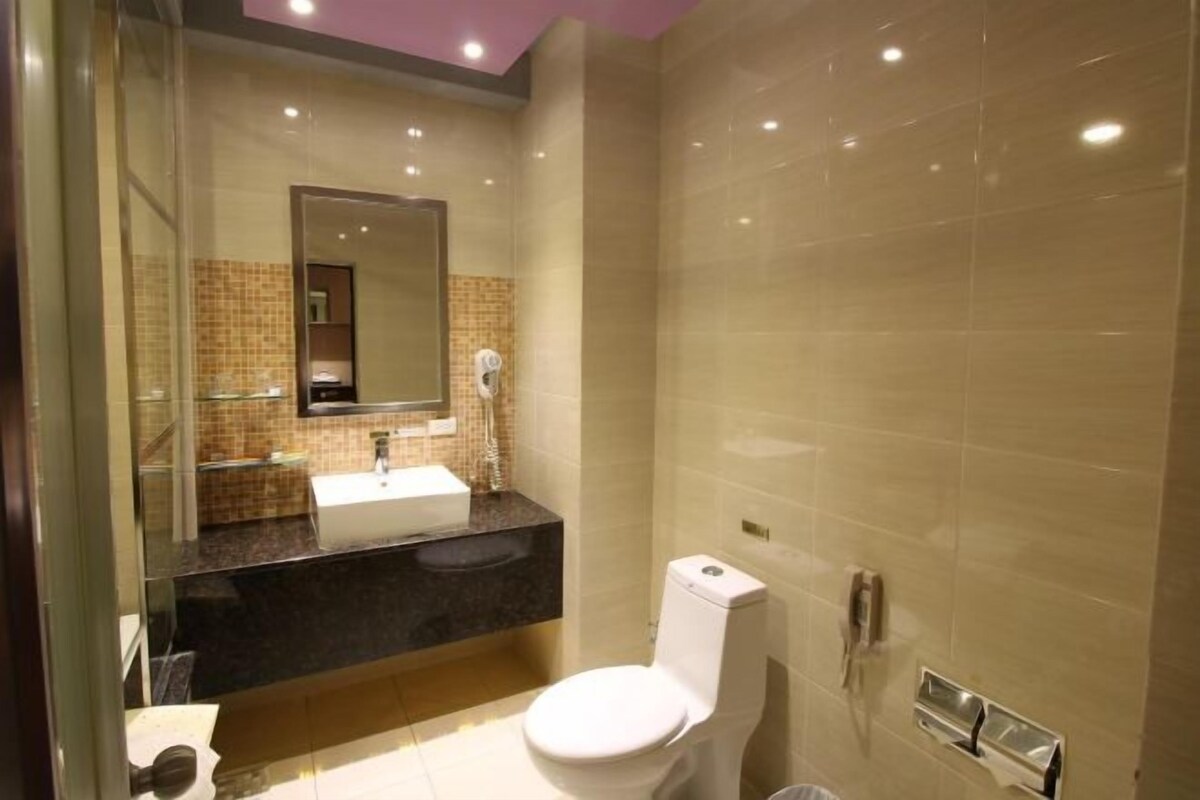 A modern bathroom with a glass shower enclosure, a white toilet, and a vanity with a sink and mirror.