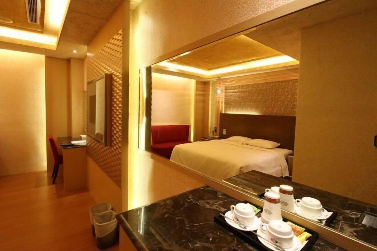 A hotel room with a bed, a desk, and a dining area with a tray of breakfast items.