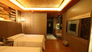 Habitación de hotel con dos camas, piso de madera, televisor y espejo.