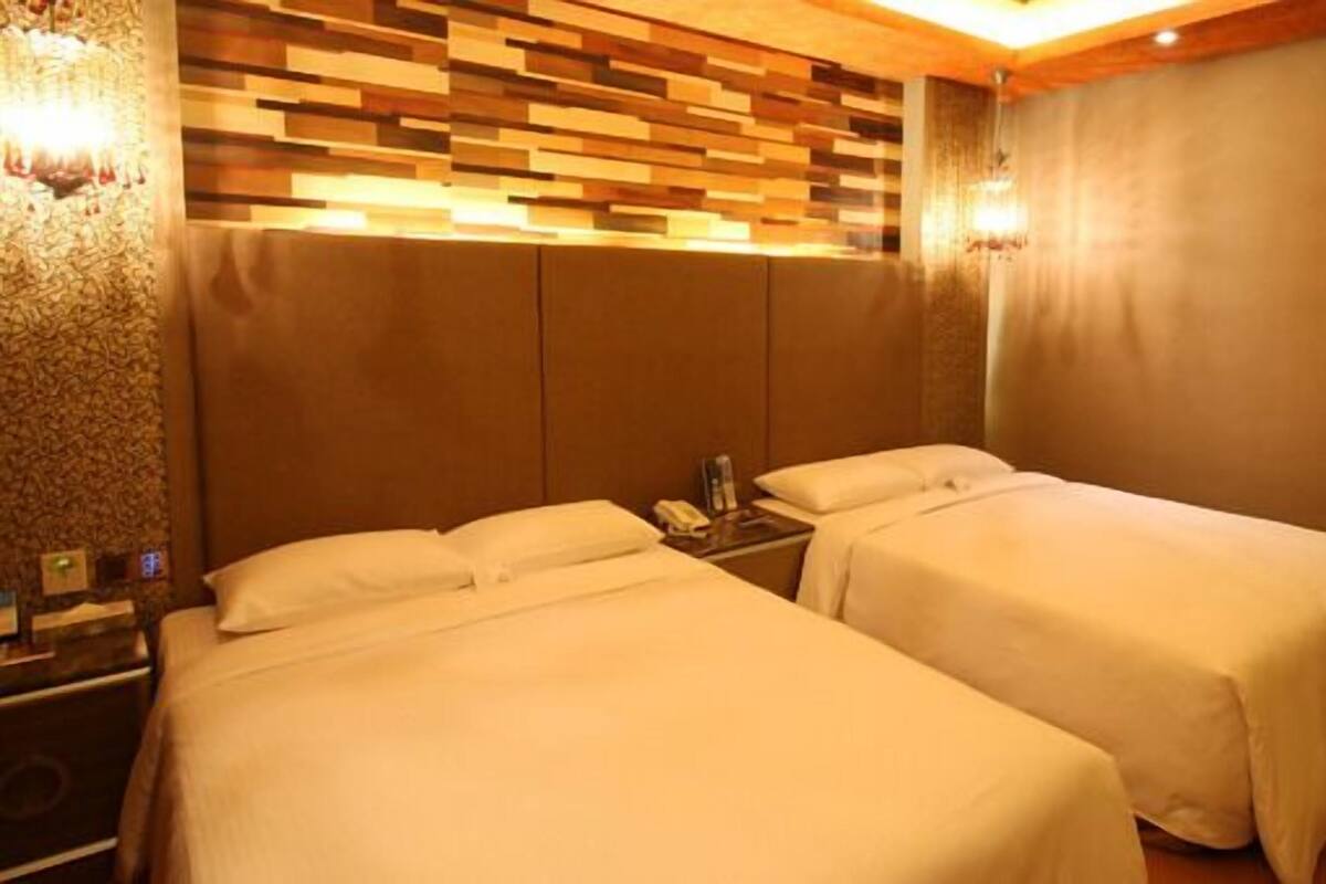 A hotel room with two beds, a wooden headboard, and a nightstand with a phone.