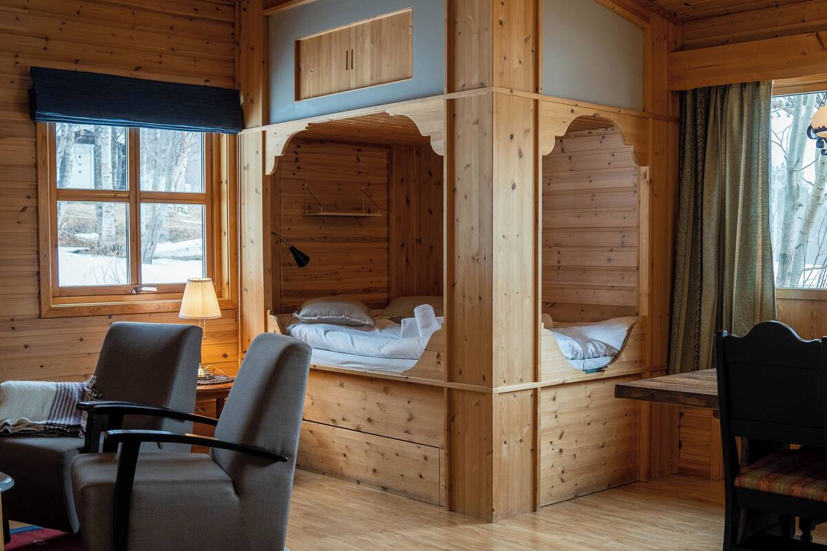 A cabin with a wooden interior, a bed, a desk, and a chair.