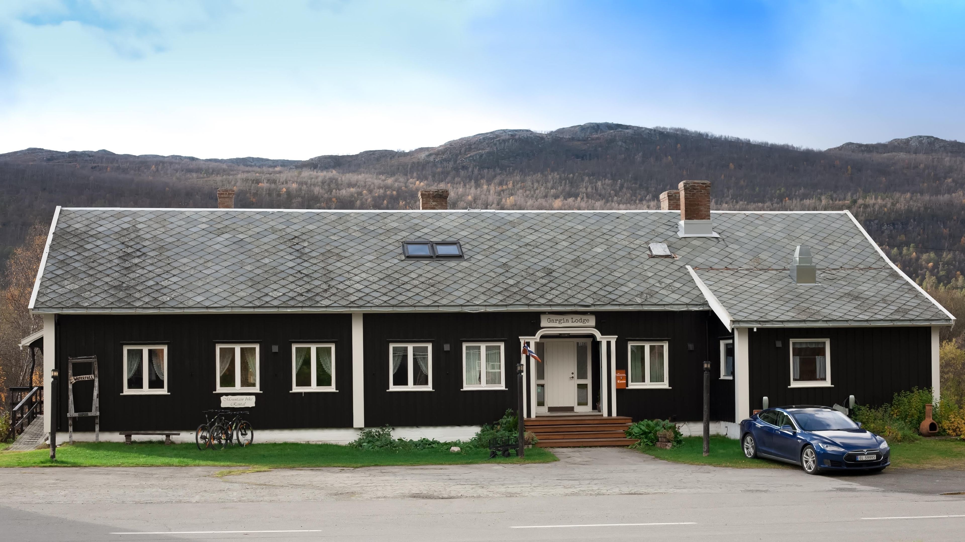 A black building with a sign reading "Gargia Lodge" and a car parked in front.