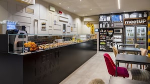 A modern cafe with a breakfast bar, seating area, and a 'MeetUp' sign. - Up Hotel (Rimini)