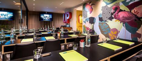 A conference room with tables, chairs, and a large mural on the wall.