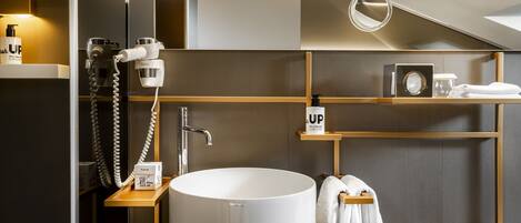 A modern bathroom with a large sink, a mirror, and a towel rack.