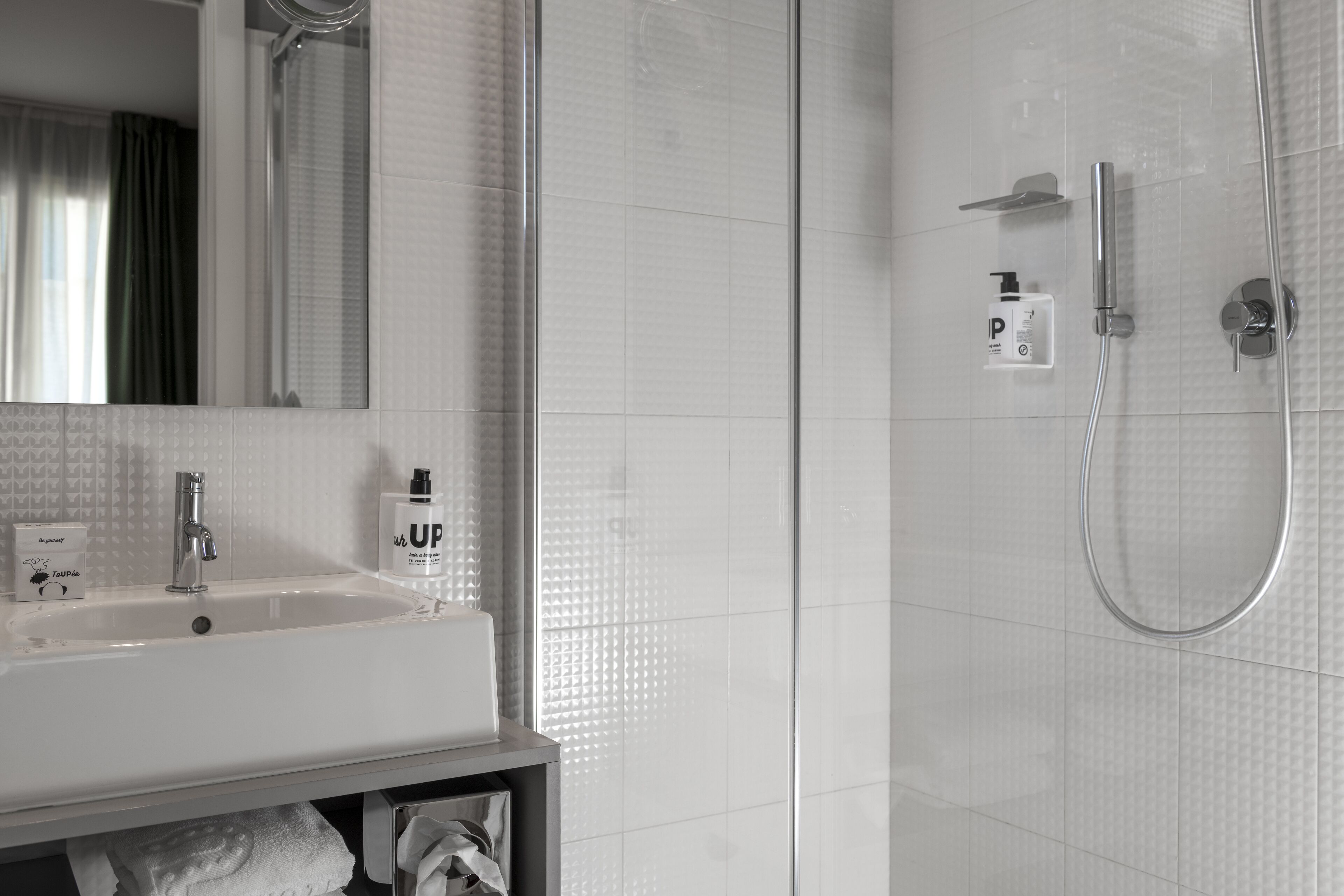 A bathroom with a white sink, mirror, and shower.