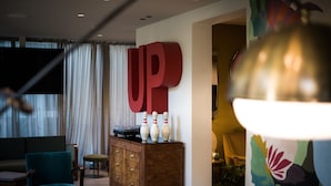 A modern living room with a large 'UP' sign, a wooden cabinet, and a sofa. - Up Hotel (Rimini)