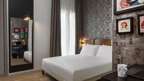 A modern hotel room with a large bed, a desk with a laptop, a mirror, and artwork on the walls. - Up Hotel (Rimini)