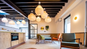 Un interior moderno con zona de cocina, asientos con otomanas e iluminación colgante.