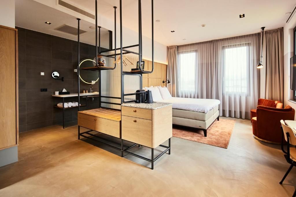 Quarto de hotel moderno com cama, mesa de cabeceira e escrivaninha com cadeira.