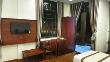 Habitación de hotel con dos camas, televisión montada en la pared, escritorio y armario.