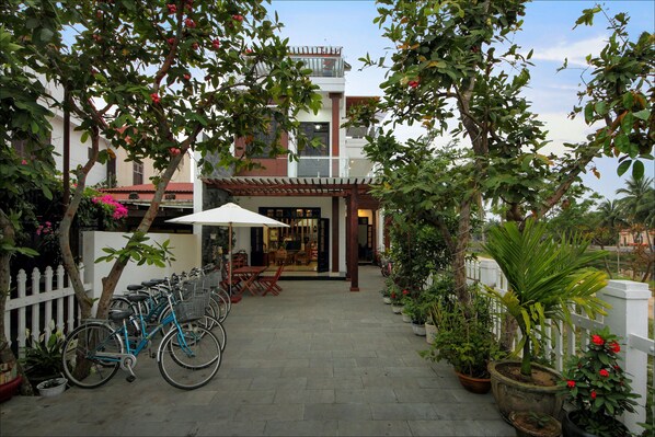 A courtyard with bicycles, potted plants, and a white fence. - Azalea Homestay (Da Nang)