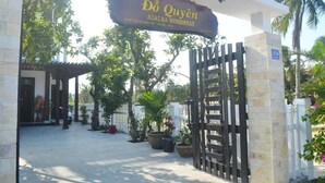 The entrance to Đồ Quyến Azalea Homestay with a gated entrance, potted plants, and a covered area with a white fence. - Azalea Homestay (Da Nang)