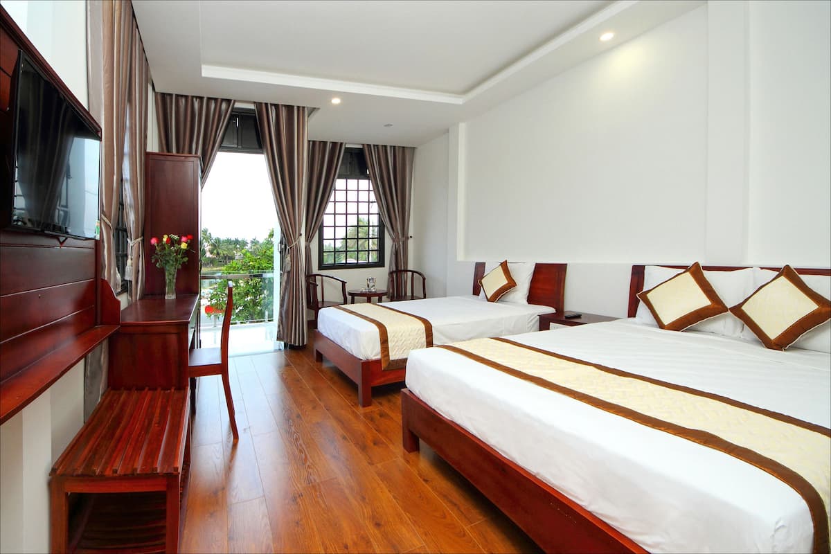 A hotel room with two beds, wooden furniture, a TV, and a window with curtains.