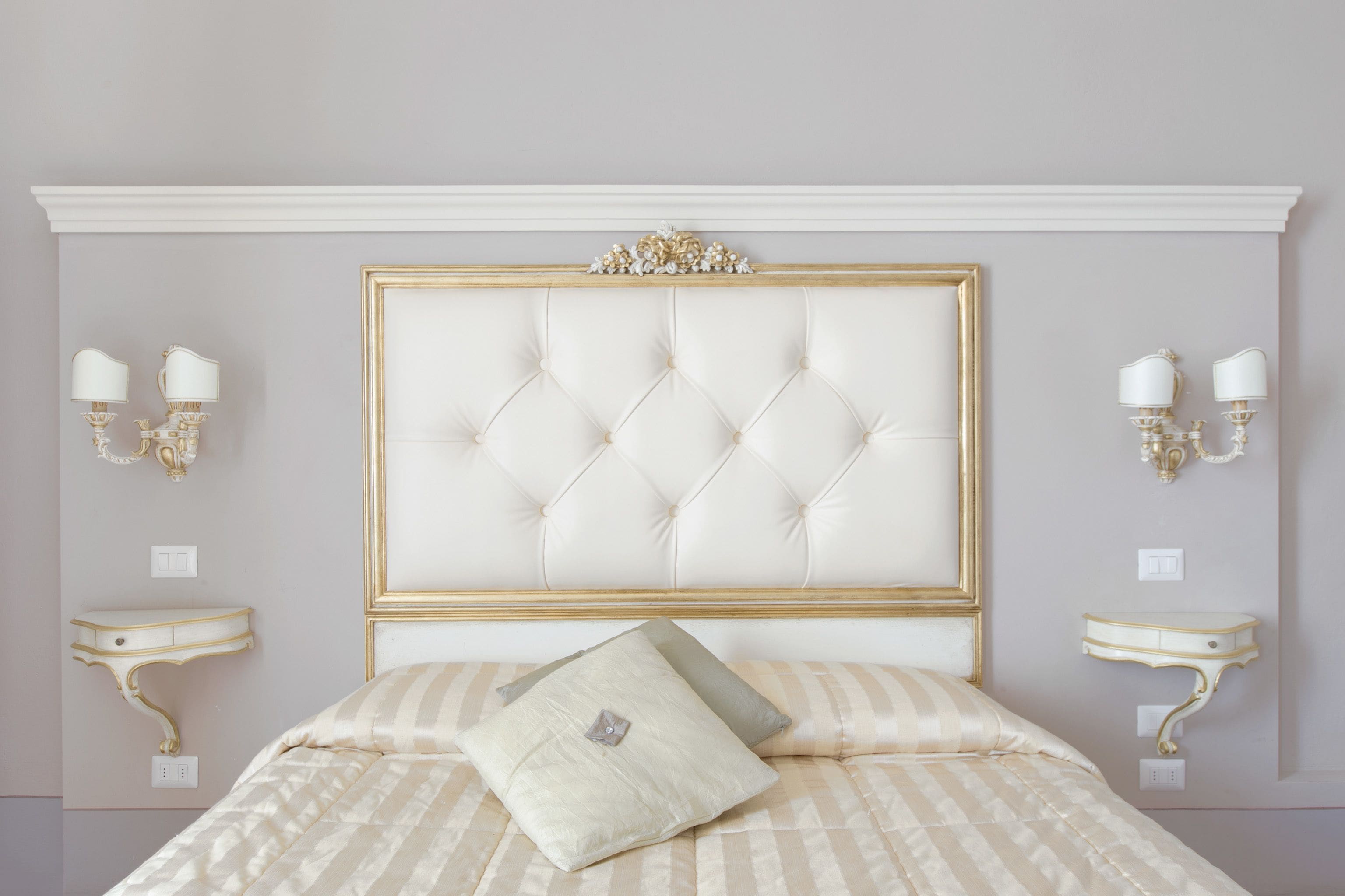 A bedroom with a tufted headboard, two bedside tables with lamps, and a bed with striped bedding.