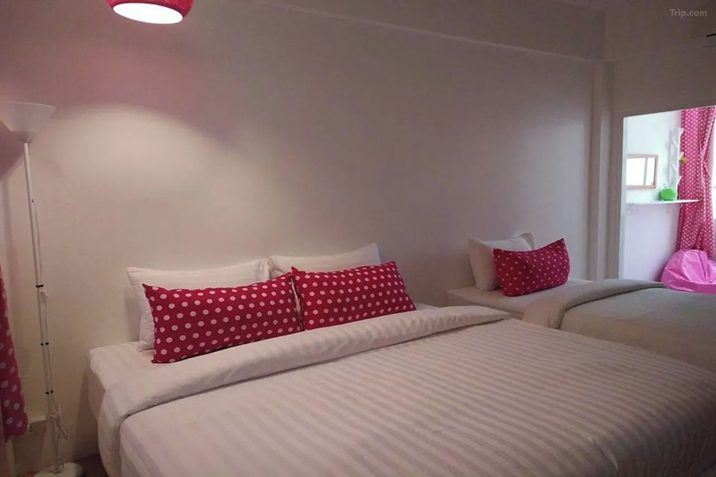 A hotel room with two beds, white bedding, and red polka dot pillows.