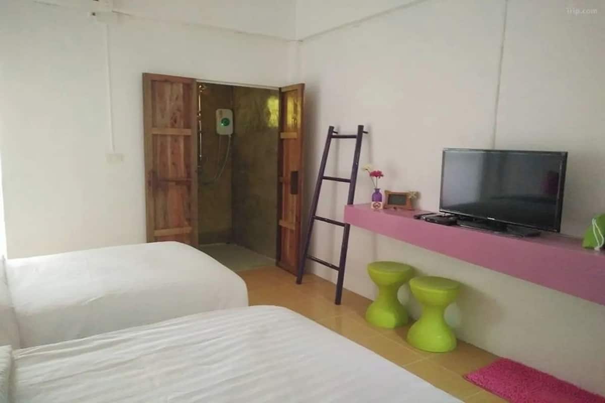 A small room with two beds, a TV, a ladder, and two green stools.
