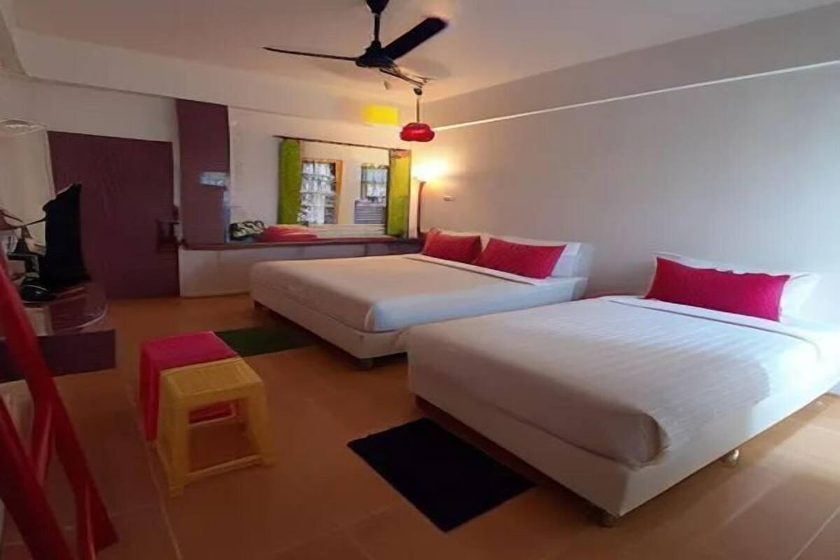 A hotel room with two beds, a ceiling fan, a small table, and a window with a view of the outside.
