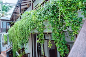 A building with a covered outdoor area featuring a staircase and a wall covered in green foliage. - Riverside Plum Garden Homestay (Da Nang)