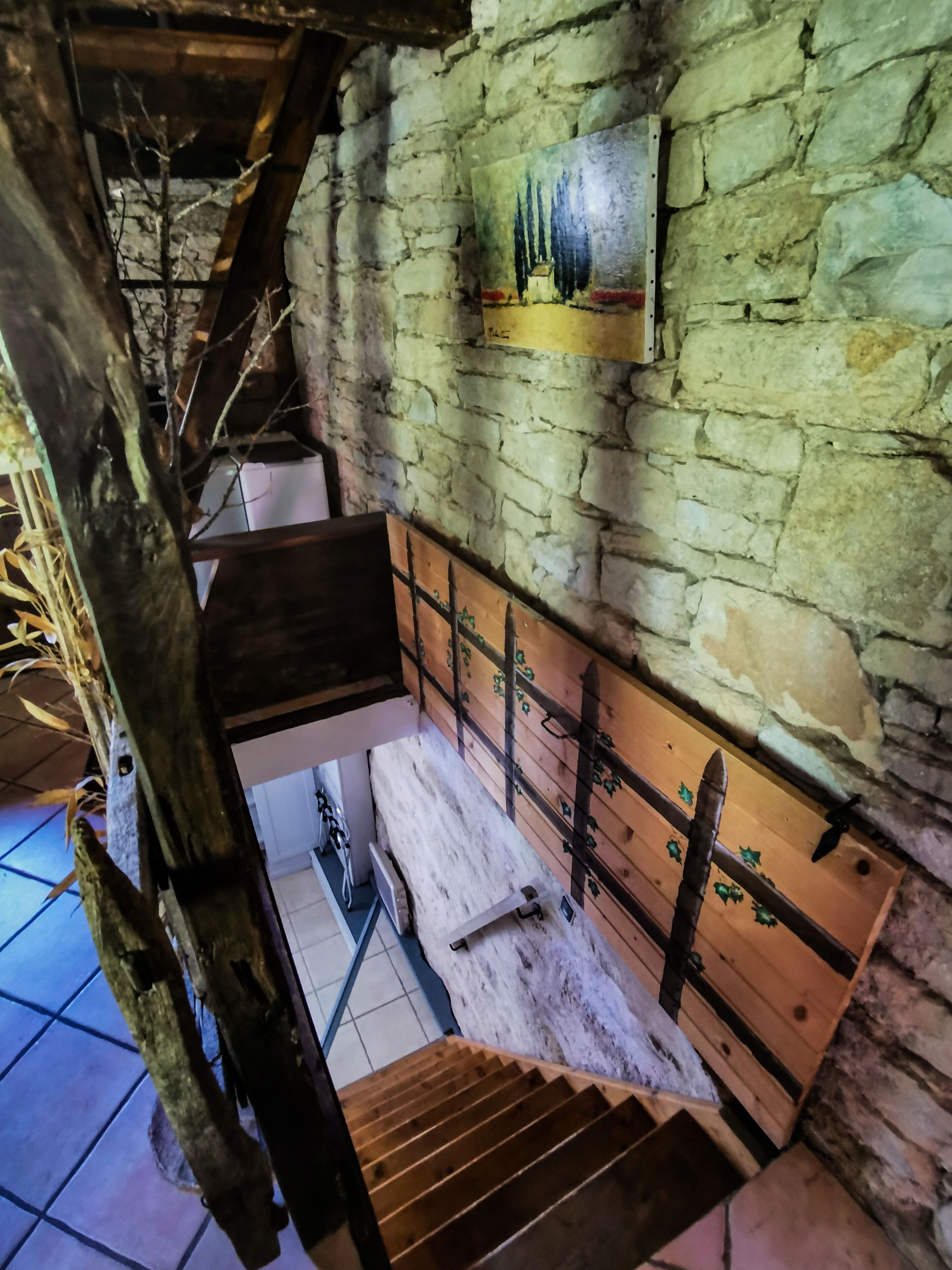 Una escalera rústica con barandillas de madera y un muro de piedra.