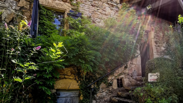 Ein Steinhaus mit einer Holztür und einer Treppe, die nach oben führt, sowie ein Schild, das ein Restaurant anzeigt.