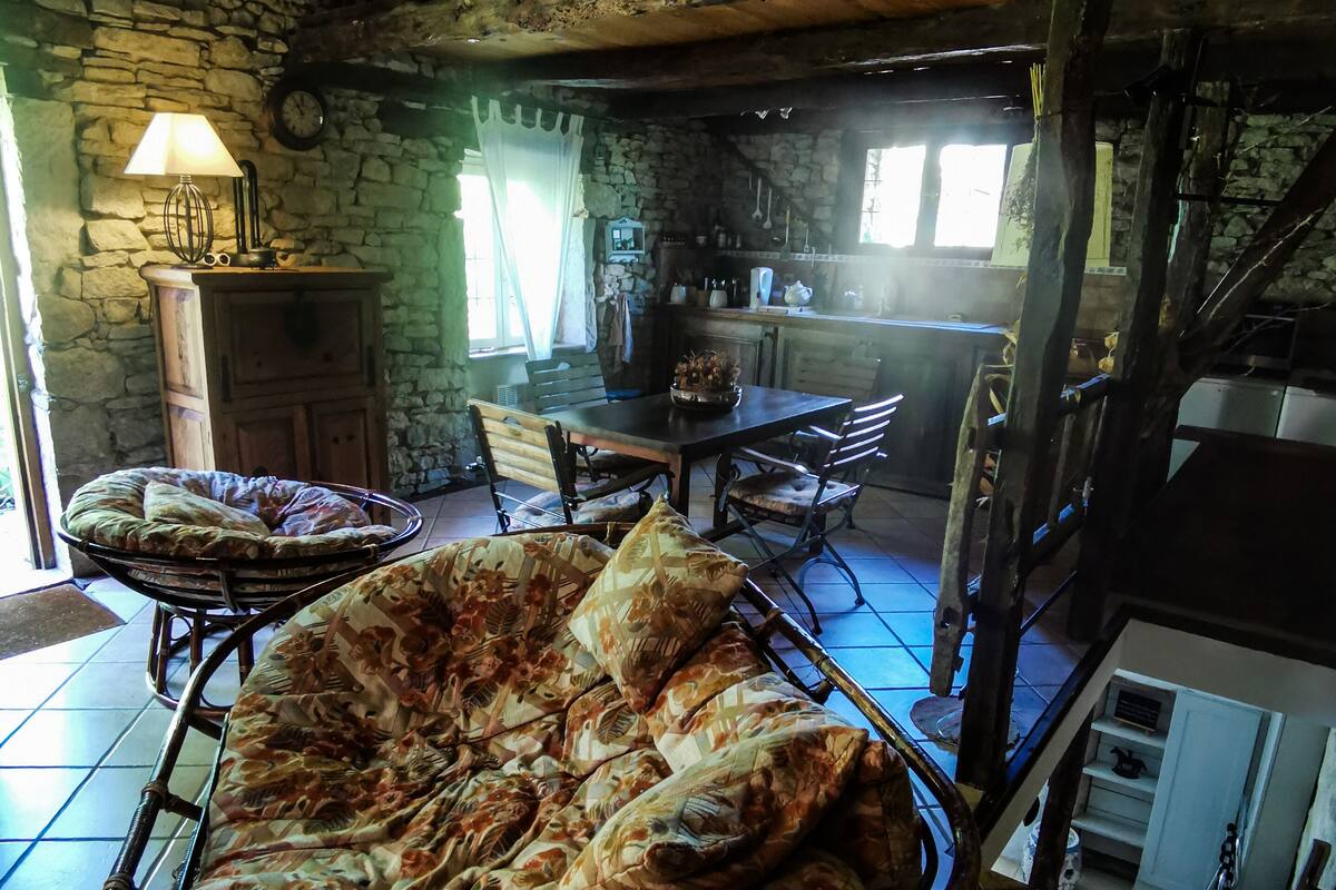 Un intérieur rustique avec un mur en pierre, des meubles en bois et un plafond haut.