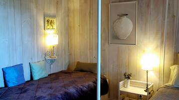 A room with two beds, wooden walls, and a white metal bed frame.
