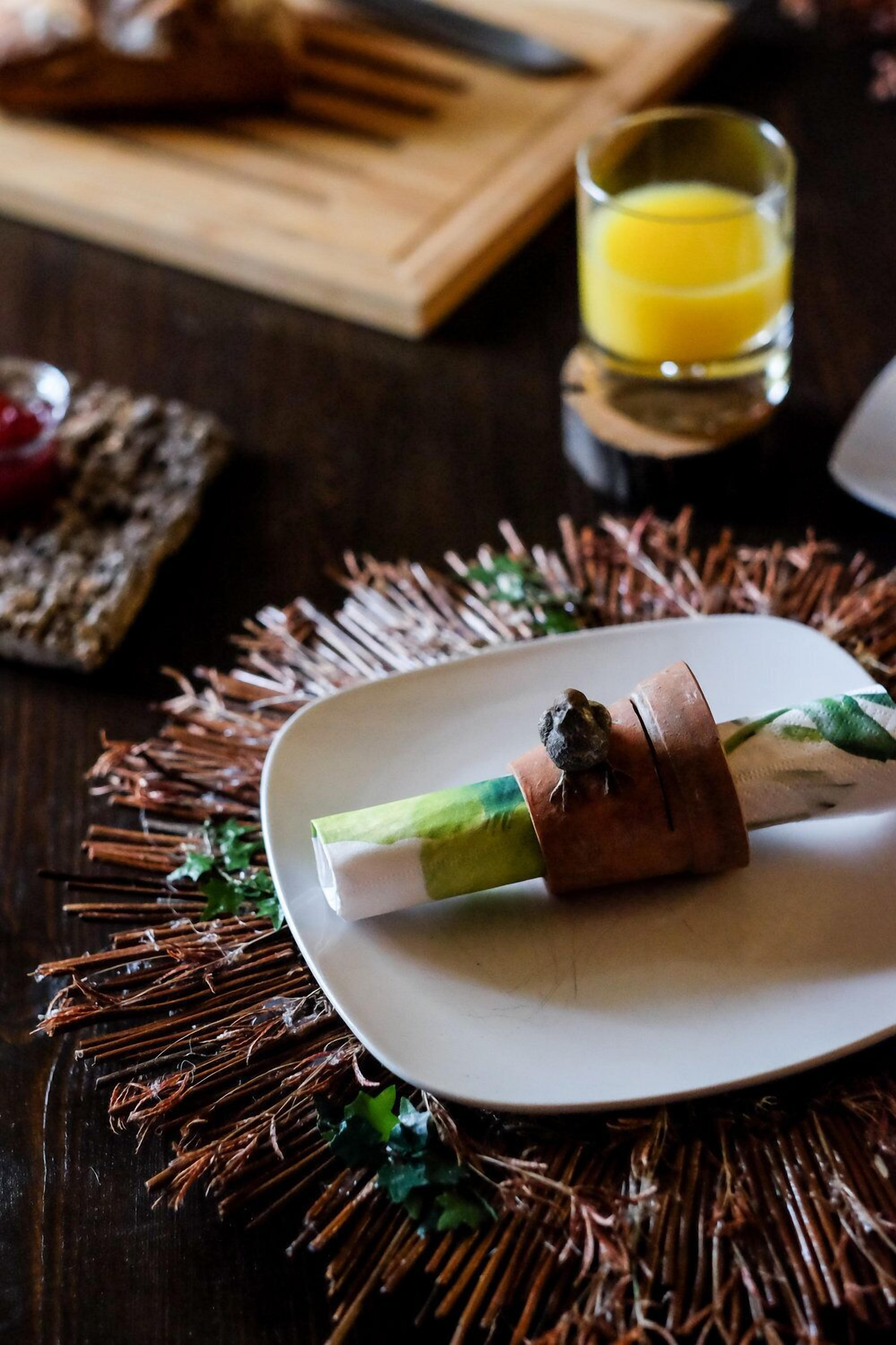 Un piatto con un rotolo, un bicchiere di succo d'arancia e un tagliere di legno con un coltello sullo sfondo.