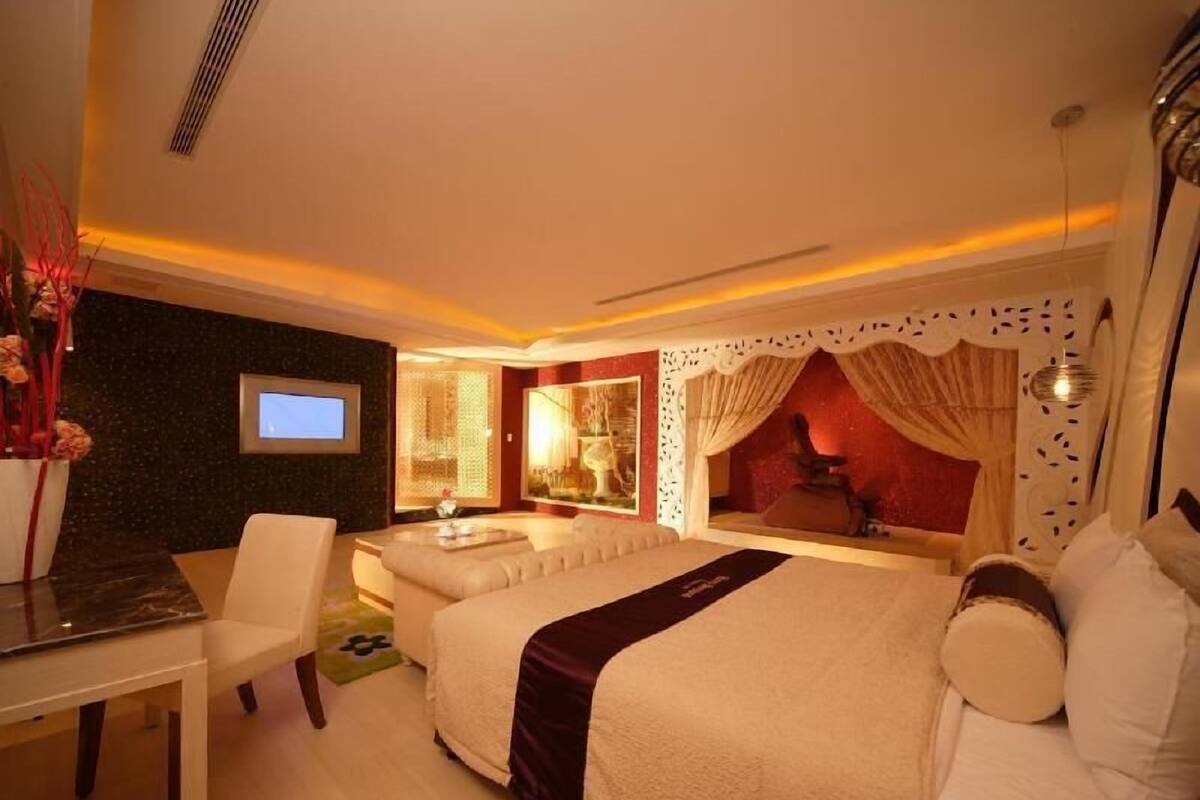Une chambre d’hôtel avec un lit, un canapé, un bureau et une télévision.